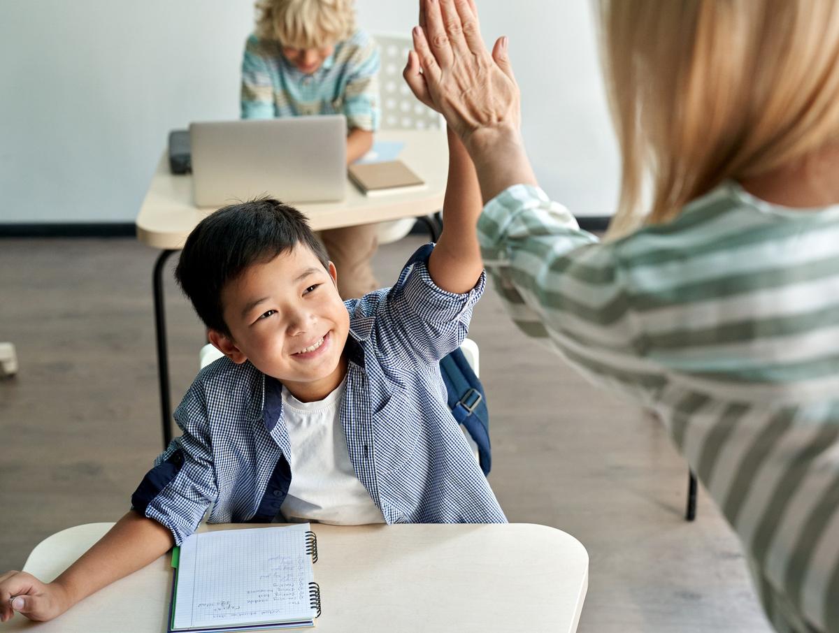 A teacher working beside a student